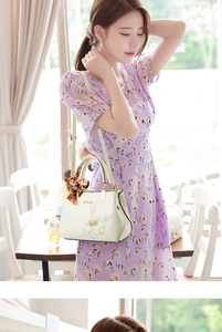 Close-up of floral embroidery detail and orange silk scarf on cream shoulder bag