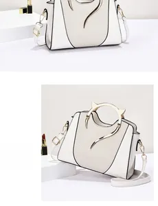 Detail view of white leather bag featuring a unique gold metal cat-ear shaped top handle