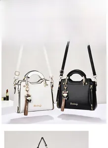 Detail of structured leather handbags in black and white with gold hardware and charm