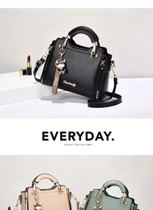 Close-up of Danbauly handbag showing semi-circular metal handles and cute cow charm