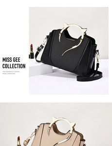 Detail of elegant cat-ear metal handles and textured leather on a chic shoulder handbag