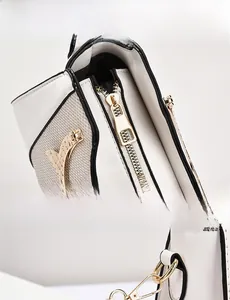 Detail view of the golden metal zipper and hardware on a bicolor textured shoulder bag