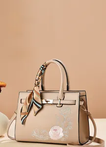 Detail of elegant beige tote bag with rose embroidery and silk scarf handle
