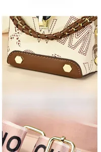 Détail du mini sac à main montrant le cuir imprimé et les rivets hexagonaux dorés à la base