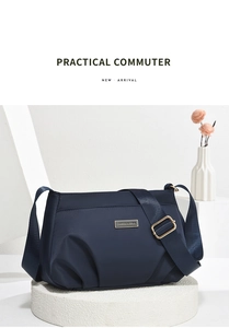 Close-up of a navy blue nylon crossbody bag with gold metal hardware and brand logo plate