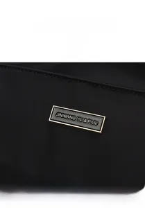 Detailed shot of rectangular black enamel and gold metal logo plate on nylon bag