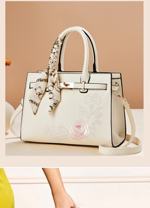 Detail of cream crossbody bag featuring elegant pink rose embroidery and chain silk scarf