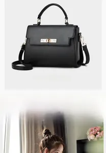 Detail of black litchi grain leather handbag featuring a golden metal twist lock closure