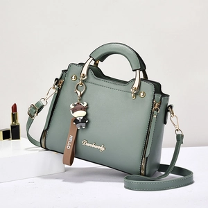 Green leather tote bag with gold logo and cute cow charm shown from 45-degree angle