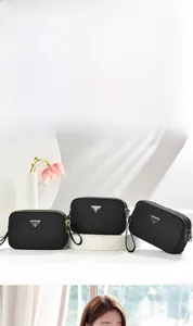 Detail of three black nylon crossbody bags with double zippers and triangle metal logo