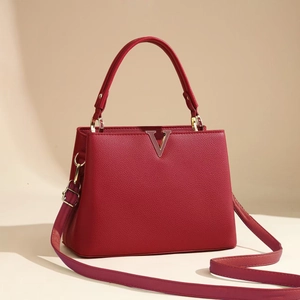 Detail of red lychee grain leather handbag with gold V-logo and sturdy top handle