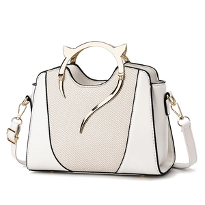 Modern white shell handbag with gold cat-ear handles and adjustable shoulder strap