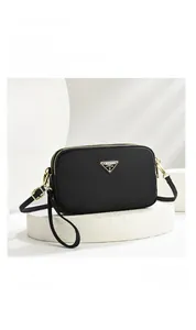 Detail of black nylon camera bag with double gold zippers and a metallic logo