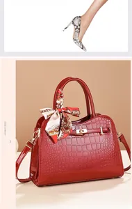 Detail einer roten Handtasche aus Lackleder mit Krokoprägung und dekorativem Seidentuch