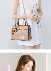 Detail of beige embroidered handbag with floral patterns and silk scarf wrap on the handle