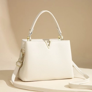Detailed close-up of ivory pebble leather handbag with gold V-shaped metal buckle accent