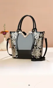 Detail der glänzenden schwarzen Handtasche mit Paillettenblumen und goldenem V-Metalllogo