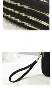 Detail of black nylon multi-zippered pouch showing gold hardware and stitching