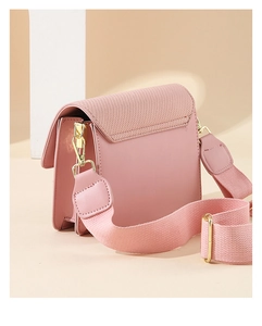 Pink crossbody bag featuring canvas texture, wide fabric strap, and gold metal hardware