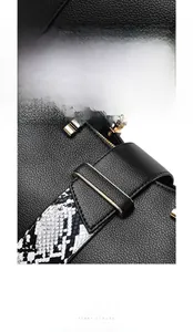 Detail of black lychee grain leather handbag with gold hardware and snakeskin strap