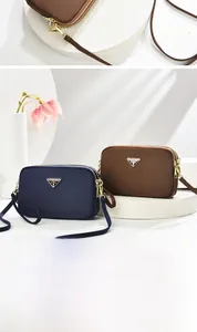 Detailed view of navy and brown mini crossbody bags with triple zipper and gold hardware