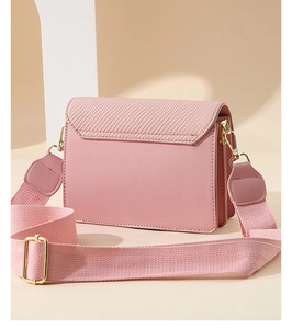 Detail of pink crossbody bag featuring woven texture flap and golden hardware accents