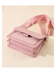 Detail of pink crossbody bag with woven texture, dual compartments and wide fabric strap