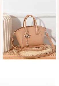 Close-up of beige pebble leather tote with elegant bow charm and chain detail