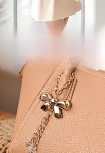 Close-up of golden butterfly charm on premium pebble leather handbag for women