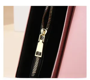 Detail of premium gold metal zipper on a pink crossbody bag with smooth texture