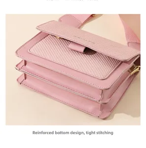 Detail of pink crossbody bag showing the reinforced bottom stitching and gold lock