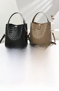 Detail of woven bucket bags in black and khaki with gold-tone hardware and straps