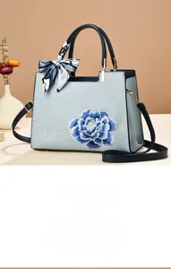 Détail de broderie de pivoine bleue sur sac bleu clair avec foulard en soie au manche