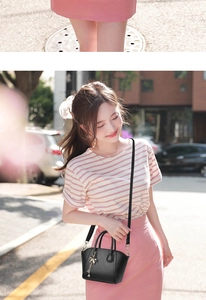 Litchi texture black handbag with metal bow tassel shown on model in street setting