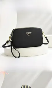 Detail of black nylon crossbody bag with triple zipper pockets and metal triangle logo