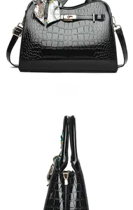 Detailansicht der schwarzen Lackledertasche mit Krokostruktur, Goldschloss und Seidenschal