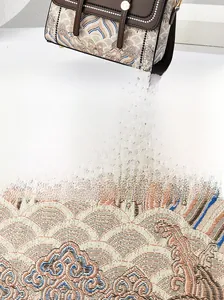 Dettaglio del ricamo tradizionale su borsa in pelle marrone e beige con piedini in metallo