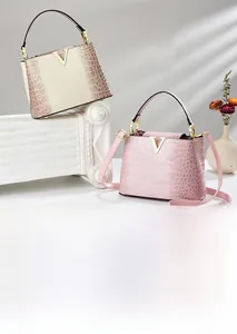 Close-up of golden V-shaped buckle and gradient crocodile texture on elegant tote bag