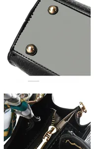 Nahaufnahme der Bodennieten und glänzenden Krokodilstruktur einer schwarzen Handtasche