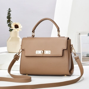 Elegant brown pebbled leather trapezoid handbag with gold hardware on a minimalist display