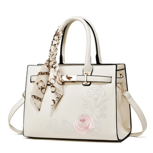 Elegant white crossbody bag with pink rose embroidery and decorative silk scarf detail
