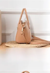 Side profile of khaki litchi leather shell bag with gold hardware and removable strap