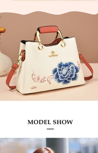 Weiße Handtasche mit blauer Blumenstickerei, Perlendetails und braunem Lederriemen