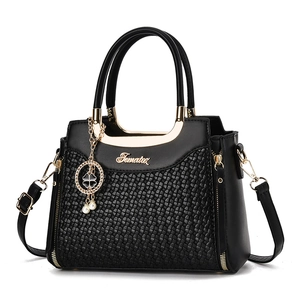 Elegant black woven leather tote bag with gold circular handles and pearl clover charm