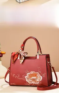 Détail du sac de mariée rouge avec broderie de pivoines et foulard en soie décoratif