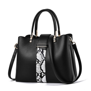 Black leather handbag with snakeskin pattern and gold hardware on white background
