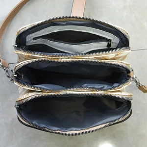 Cream printed crossbody bag with three main zip compartments and a grey interior lining