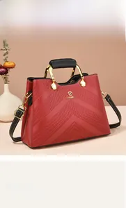 Detail of burgundy leather tote with V-shaped quilting and gold metal handle