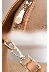 Detailed close-up of light brown shell bag featuring durable golden metal hardware zippers
