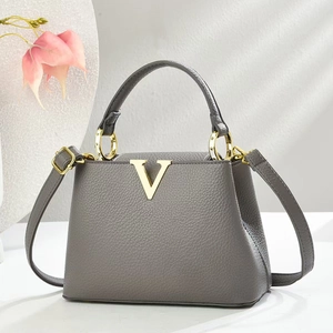 Graue Handtasche aus Litschi-Leder mit goldenem V-Logo und Schultergurt auf Weiß